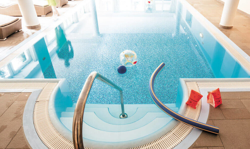 Kleiner Innenpool mit Spielzeug wie Schwimmnudeln, Wasserball und Schwimmflügeln am Rand im Familienhotel mit Schwimmbad im Harz