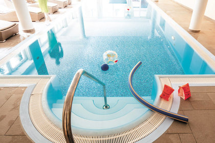 Kleiner Innenpool mit Spielzeug wie Schwimmnudeln, Wasserball und Schwimmflügeln am Rand im Familienhotel mit Schwimmbad im Harz