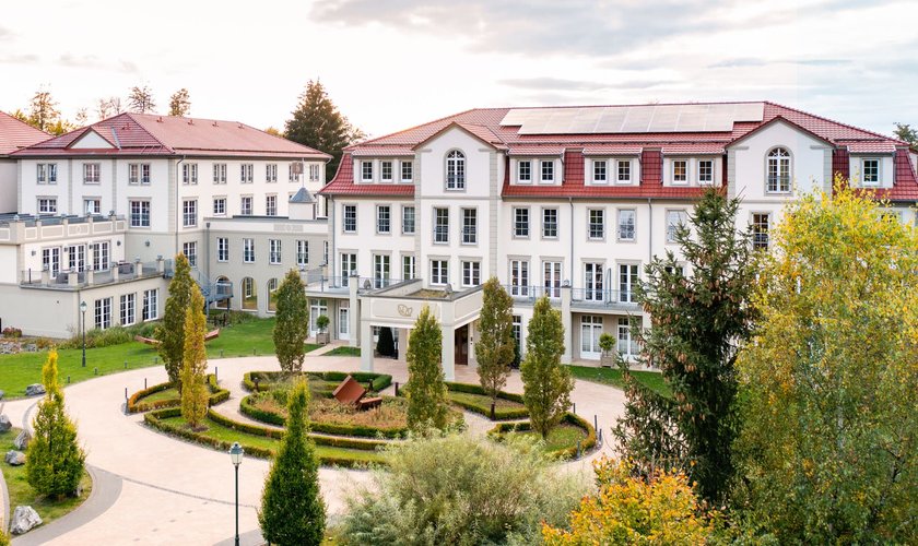 Aerial view of a hotel with red roofs, surrounded by autumn-coloured forests