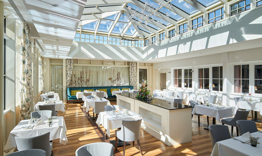 Helles, elegantes Restaurant mit großen Fenstern und Glasdach im Wellnesshotel im Harz.