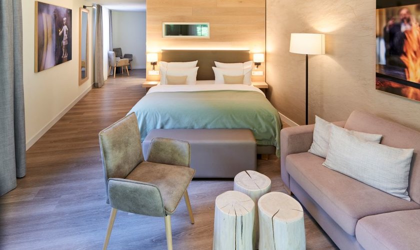 Eine Nacht geschenkt In einem modernen Hotelzimmer steht ein gemütliches Doppelbett mit indirekter Beleuchtung und warmen Wandtönen.