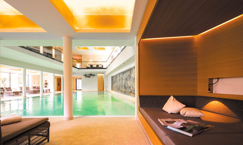 Ein luxuriöser Innenpool mit warm beleuchteten Decken und gemütlichen Sitzbereichen, die zum Entspannen einladen