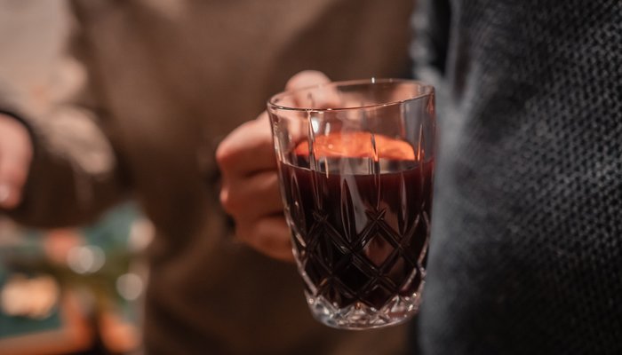 Person hält ein Glas mit Glühwein im Wellnesshotel im Harz