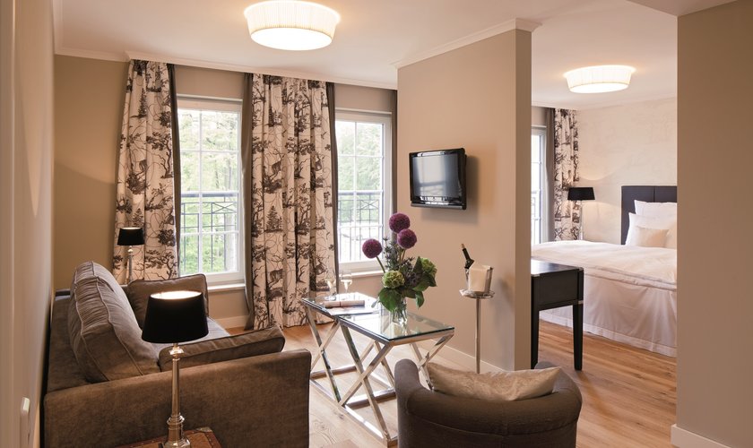 Vitalzimmer Deluxe mit geteiltem Raum für Wohn- und Schlafbereich und bodentiefen Fenstern.