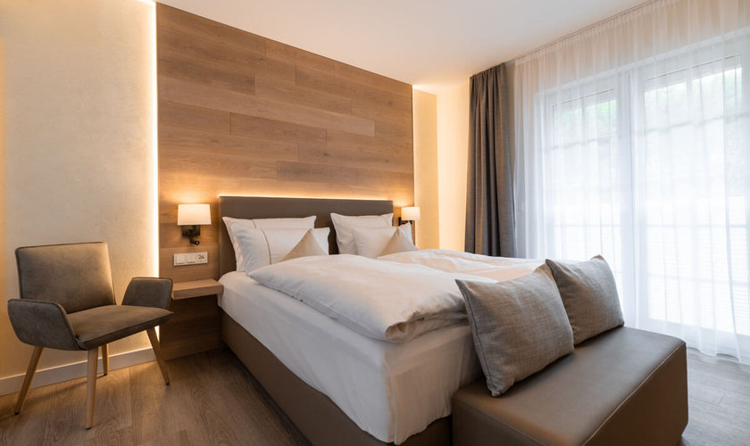 Gemütliches Schlafzimmer mit modernem Doppelbett, weichen Kissen und großem Fenster in einer Private Spa Suite im Harz