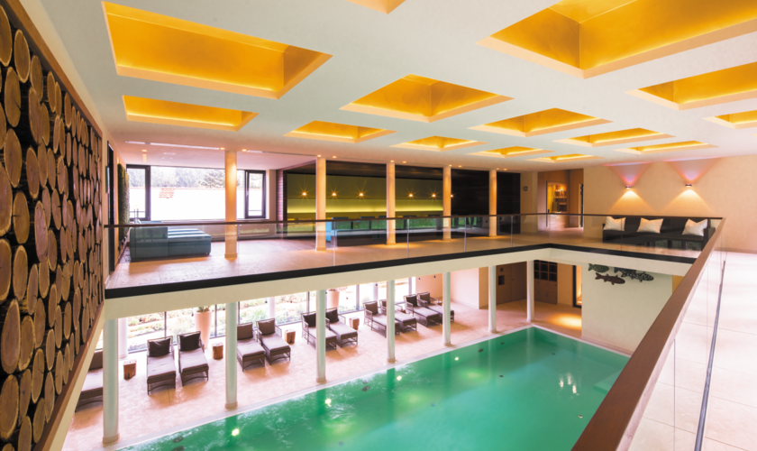 Der Pool im Schindelbruch mit Holzfassade und gemütlichem Lichtspiel.