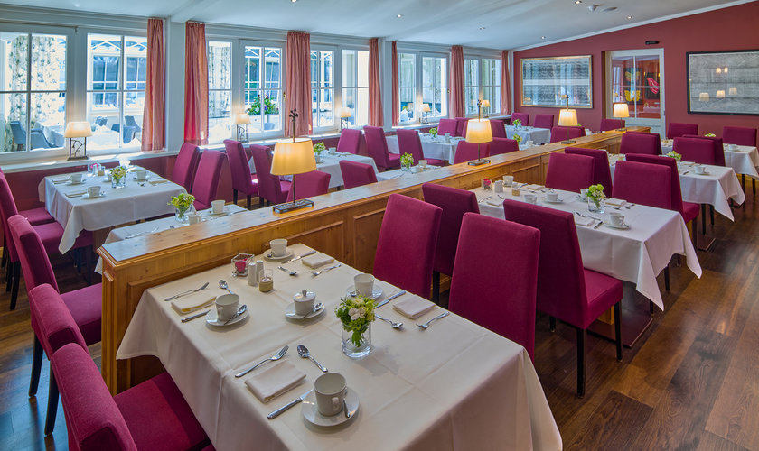 Ein gemütlicher Speisesaal mit weiß gedeckten Tischen und roten Stühlen im Restaurant in Stolberg, Harz.