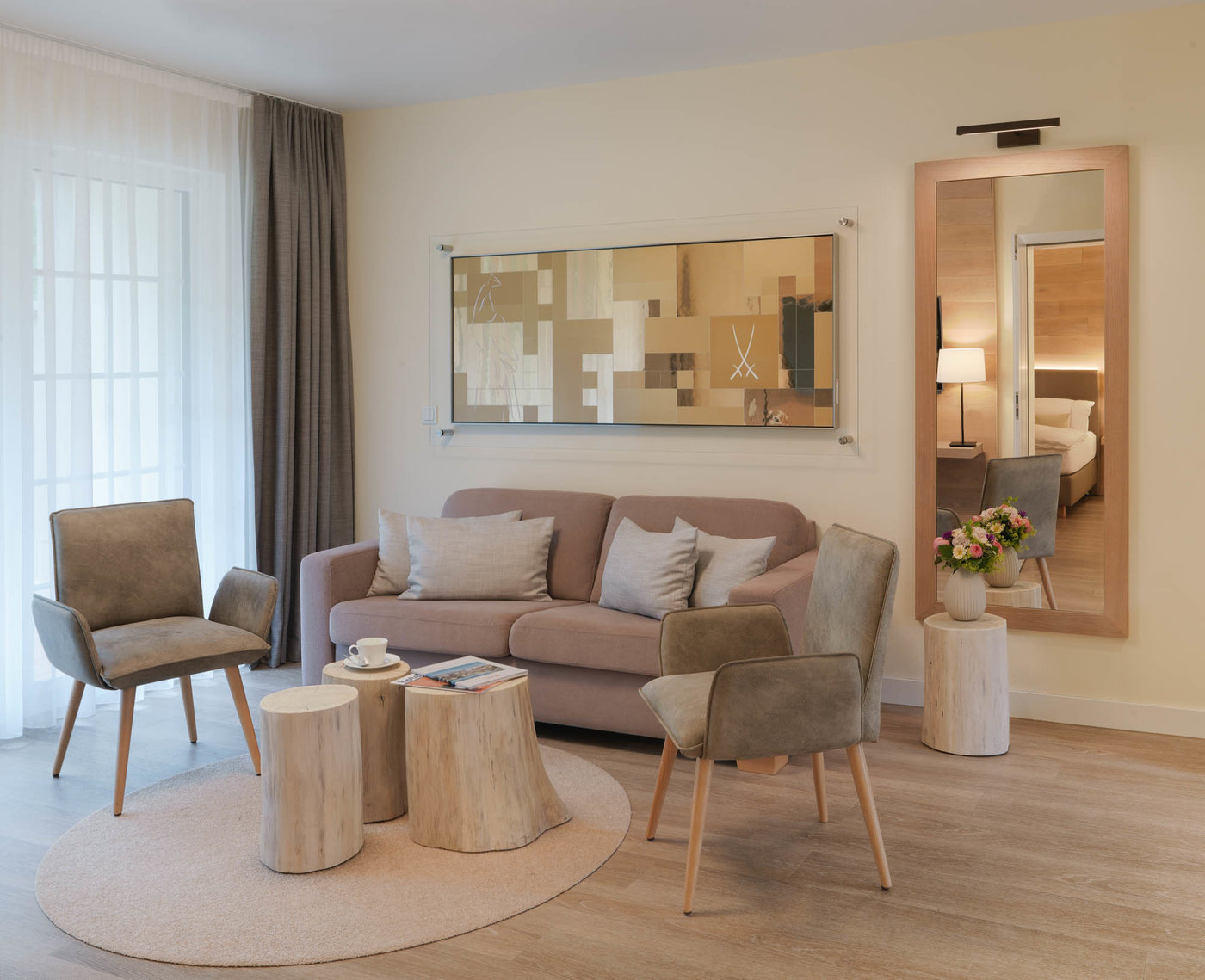 Gemütliche Sitzecke mit moderner Couch, zwei Stühlen und rustikalen Holztischen in einer Private Spa Suite im Harz