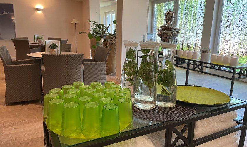 Im Wellnessbereich gibt es ein Bistro, in dem runde Tische und Stühle stehen und kostenloses Wasser mit Zitronenscheiben.
